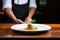 chef garnishing arancini plate with basil leaves