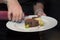 Chef garnishing venison dish in a plate to be ready to serve, gourmet food, cooking