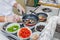 Chef gloved hands cook vegetables and other ingredients on a gas stove in frying pan