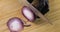 Chef in gloves cooking cutting fresh red onion on wooden board, hands closeup.