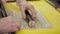 A chef with gloves on a yellow table forms rolls with a mat.