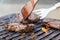 Chef grilling beef steaks on open flame BBQ.