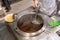 Chef hand boiling noodle with strainer in Thai chamber pot with variety of soup