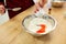 Chef hands adding food color into bowl with flour