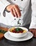 Chef, hands and bowl with pasta recipe in kitchen for fine dining, serving or cooking at restaurant. Closeup of person