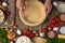 Chef hands carefully puts the rolled dough into baking dish on wooden table with variety of ingredients and flour background.