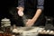 Chef hands are clapping wheat flour under rolled dough