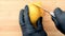 Chef hands in gloves cutting yellow lemon on chopping board into slices with sharp knife closeup.