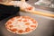 Chef hands with gloves holding pepperoni slices for pizza toppings