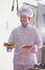 Chef holding salad in plate and fresh cherry tomatoes in tray at restaurant