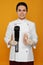 Chef holding sous vide cooker and meat in vacuum pack on orange background