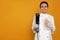 Chef holding sous vide cooker and meat in vacuum pack on orange background. Space for text