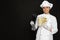 Chef holding sous vide cooker and vegetables in vacuum packs on black background. Space for text