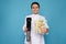 Chef holding sous vide cooker and vegetables in vacuum packs on light blue background