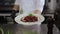 Chef holds a plate of beef steak and strawberry sauce in the restaurant kitchen.