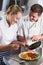 Chef Instructing Trainee In Restaurant Kitchen