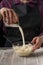 The chef keeps the dough over the working surface. A dark background