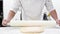 Chef kneading dough with rolling pin at commercial kitchen. Pastry Chef kneading dough on the table at pastry shop.