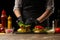 The chef lays out a fresh salad on a burger, with ingredients in the background. Horizontal photo, Tasty and unhealthy food, fast