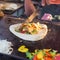 Chef making chicken with grilled vegetable tortilla wrap on street stall.