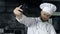 Chef making photo at kitchen. Portrait of chef taking selfie at mobile phone.