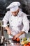 Chef male with knife at restaurant kitchen. Professional chef cutting tomato.