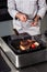 Chef man prepare steak at griddle pan. Closeup chef hand cooks grill beef.