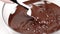 Chef melts dark chocolate couverture callets in glass bowl slow mo close up