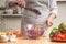 The chef mixes the salad, stir, in the process of a vegetarian salad in the home kitchen. Light background for restaurant menu