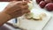 Chef peeling yellow onion on marble cutting board, close up video