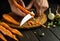 The chef peels raw carrots with a knife while preparing a vegetarian meal or vegetable borscht for dinner