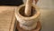 Chef pounding Spicy shrimp paste in a brown stone mortar.