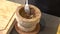 Chef pounding Spicy shrimp paste in a brown stone mortar.