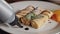 Chef pouring chocolate syrup on tasty delicious cottage cheese peach pancakes on plate on table