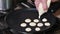 Chef pouring dough is into pan for cooking mini pancakes.