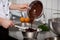 Chef Pouring Liquid Chocolate In Bowl At Kitchen Counter