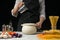 The chef pours water into the pan, on a black background, with pasta on the table, vegetables and spaghetti, mushrooms. The concep