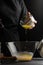 The chef prepares the dough for pouring yeast, for baking, bread, pizza, or pasta. on a black background, vertical photo