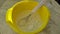 The chef prepares the flour pancake dough by hand whisking it in a yellow bowl with a whisk