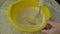 The chef prepares the flour pancake dough by hand whisking it in a yellow bowl with a whisk