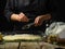 The chef prepares traditional classic Italian focaccia bread. He is rubbing cheese onto a dough in a baking dish. The ingredients