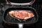 Chef preparing dry-aged beef, Sirloin with truffle oil, garlic, and black pepper seared in juicy medium-rare in cooking pan.