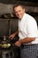 Chef Preparing Meal On Cooker In Kitchen