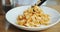 Chef puts pasta spaghetti in the plate with tongs, serving italian dish.