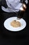 The chef puts the pasta with truffle sauce from the pan on a plate. Pasta with black truffle . Unrecognizable person. Photo on a