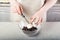 The chef puts a piece of butter in a glass bowl with chocolate