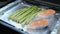 Chef puts vegetables on baking sheet. Process of cooking fish steak. Woman cooks healthy food in oven at smart kitchen. Vegetables