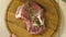 The chef puts a wooden board with a piece of raw marinated meat on a light wooden surface, a large piece of meat