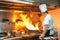 Chef in restaurant kitchen at stove with pan