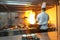 Chef in restaurant kitchen at stove with pan